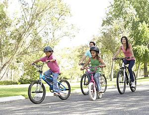 Young Family Riding Bikes In Park