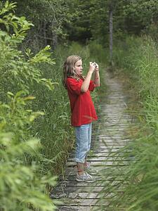 Young girl on pathway taking a picture, Lake of the Woods, Ontario, Canada