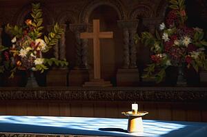 Candle, cross and flowers at an altar