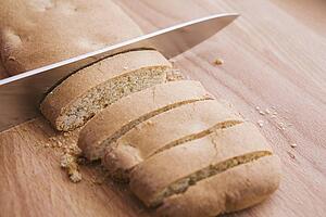 biscotti loaf being cut with a knife on a cutting board