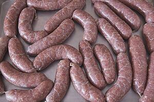 uncooked sausage on a baking sheet