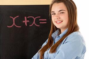 Female Student Standing Next To Blackboard