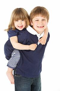 Studio Portrait Of Brother Giving Sister Piggy Back