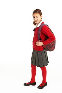 Studio Portrait Of Female Student In Uniform With Backpack