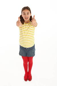 Studio Portrait Of Happy young Girl Giving Thumbs Up Gesture