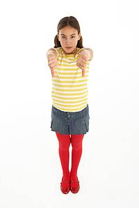 Studio Portrait Of Defiant Young Girl Giving Thumbs Down Gesture