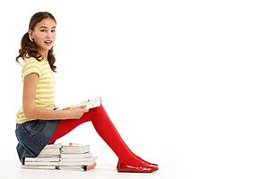 Young Girl Sitting On Pile Of Books Reading