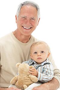 Studio Portrait Of Grandfather Holding Grandson With Teddy Bear