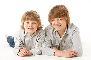 Two Young Boys Lying On Stomach In Studio