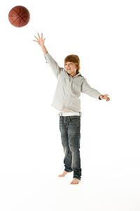 Young Boy Jumping With Basketball In Studio