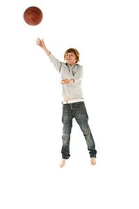 Young Boy Jumping With Basketball In Studio