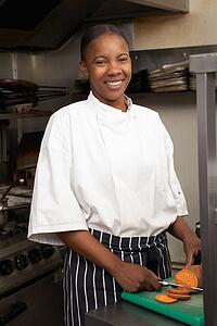 Female Chef Preparing Vegetables In Restaurant Kitchen