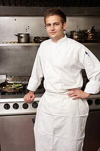 Male Chef Standing Next To Cooker In Restaurant Kitchen