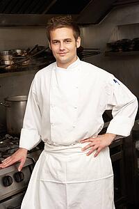 Male Chef Standing Next To Cooker In Restaurant Kitchen