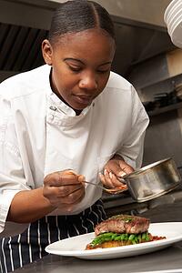 Chef Adding Sauce To Dish In Restaurant Kitchen