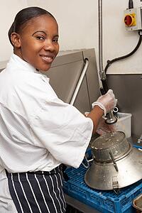 Kitchen Worker Washing Up In Restaurant Kitchen