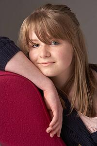 Thoughtful Teenage Girl Relaxing On Chaise Longue
