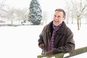 Senior Man Standing Outside In Snowy Landscape