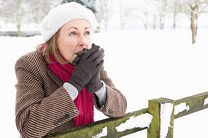 Senior Woman Standing Outside In Snowy Landscape Warming Hands