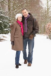 Senior Couple Walking Through Snowy Woodland
