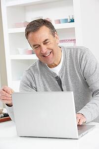 Senior Man Using Laptop At Home