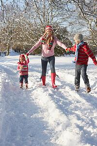 Mother Walking With Children Through Snowy Landscape