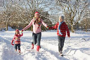 Mother Walking With Children Through Snowy Landscape