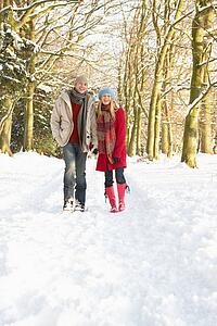 Couple Walking Through Snowy Woodland