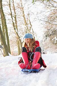 Woman Sledging Through Snowy Woodland