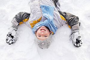 Boy Laying On Ground Making Snow Angel