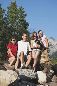 kananaskis country, alberta, canada; a family sitting on the rocks in the mountains with their dog