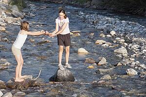 kananaskis country, alberta, canada; two girls playing on the rocks in the river