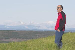 calgary, alberta, canada; a male hiker overlooking the valley with mountains