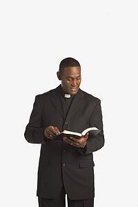 a man wearing a clerical collar and reading from his bible