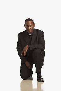 a man wearing a clerical collar kneeling in prayer