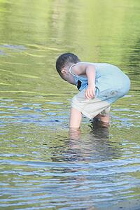 a young boy playing in the shallow water