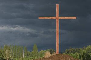 a cross on a hill with a dark sky