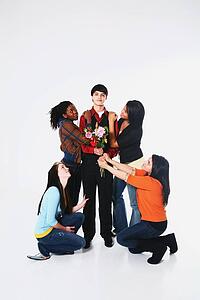 girls surrounding a boy who is holding flowers