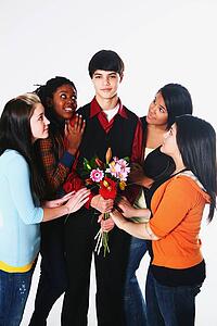 girls surrounding a boy who is holding flowers