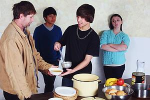 teenagers serving a meal to a man