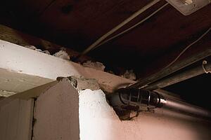 vent and plumbing pipes coming out of a broken wall