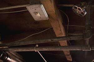 a furnace switch, valve and pipes in the ceiling