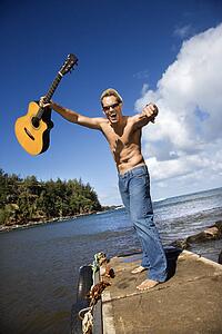 Enthusiastic Young Man With Guitar Standing Lakeside