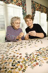 Elderly Woman and Younger Woman doing a puzzle together