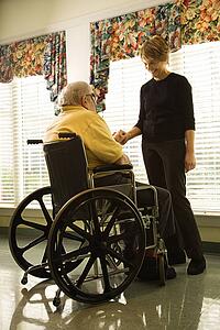 Elderly Man in Wheelchair and Young Woman