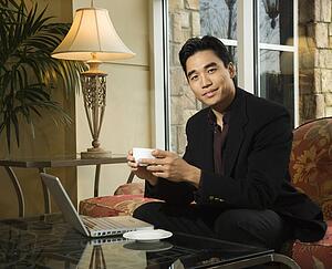 Young Businessman at Laptop Holding a Coffee Cup
