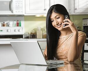 Young Woman Using Laptop and Talking on Cellphone