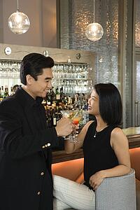 Attractive Man and Woman at Bar Having Cocktails