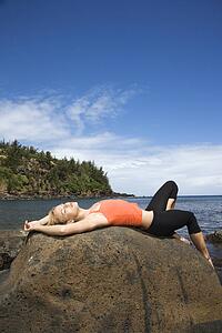 Young Woman Lying on Rock at Beach