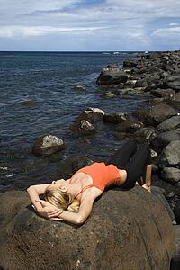 Young Woman Lying on Rock at Beach